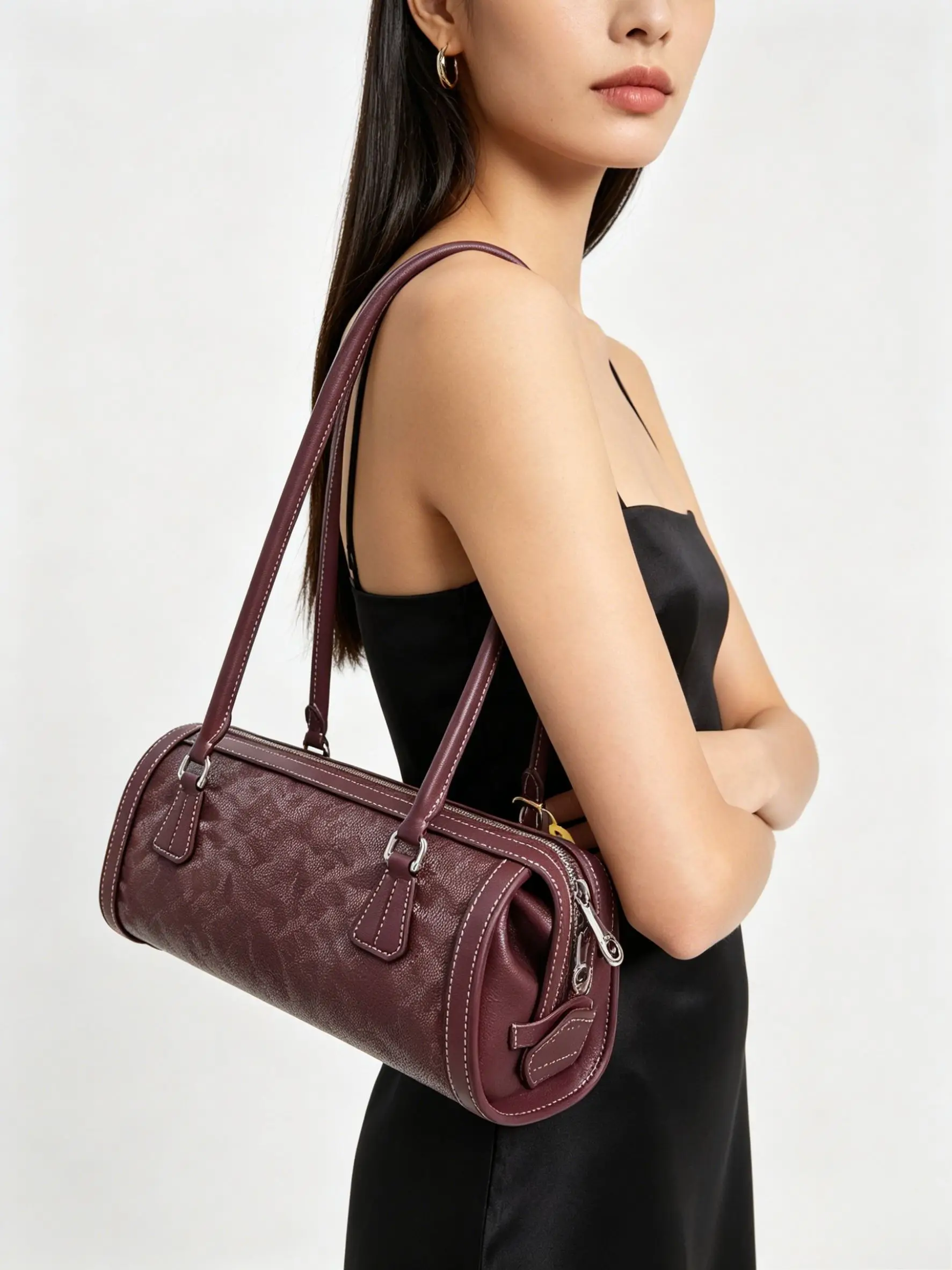 

Vintage-style cylindrical shoulder bag made of embossed leather, featuring a smooth long handle and a minimalist design.