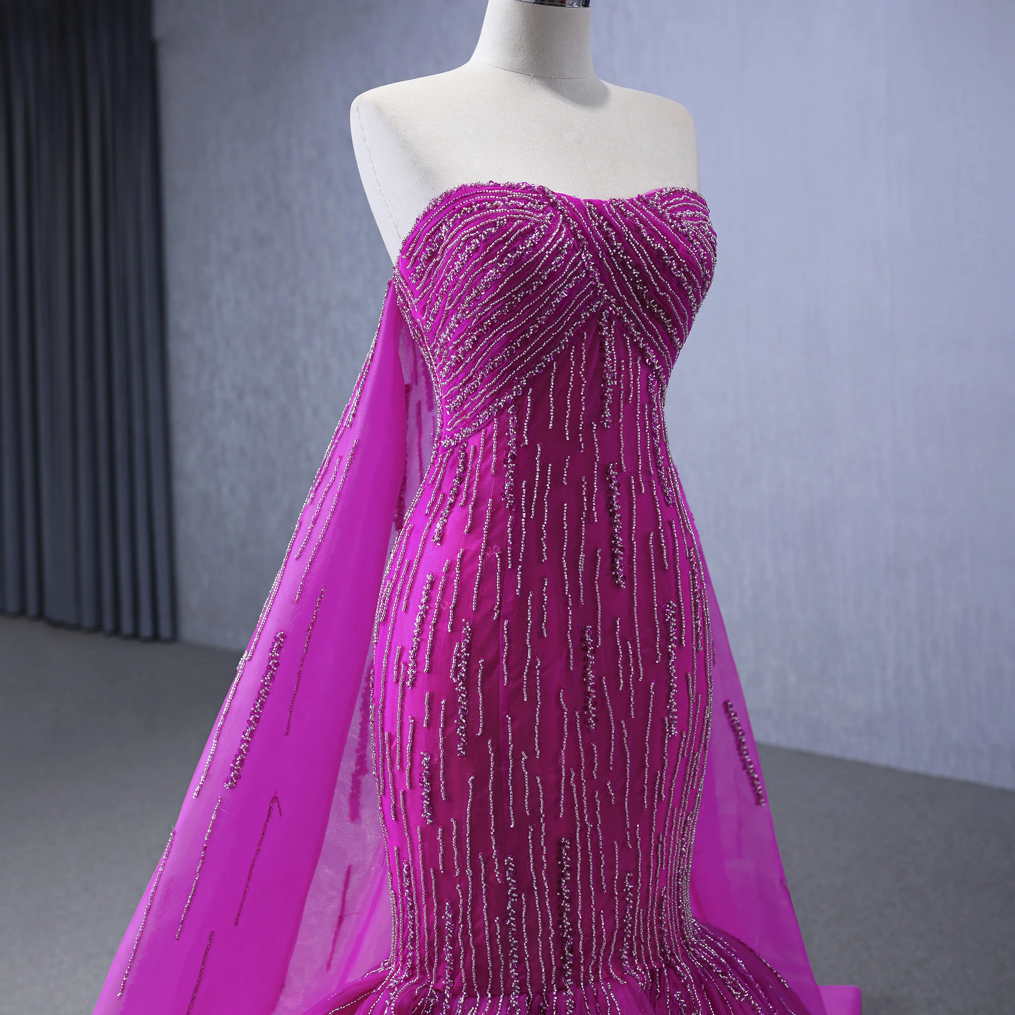 Suknia wieczorowa Rosymae, ekskluzywna, fuksjowa, zdobiona koralikami, bez ramiączek, o kroju trąbki, z peleryną na plecach, z trenem typu court, idealna na formalne okazje.