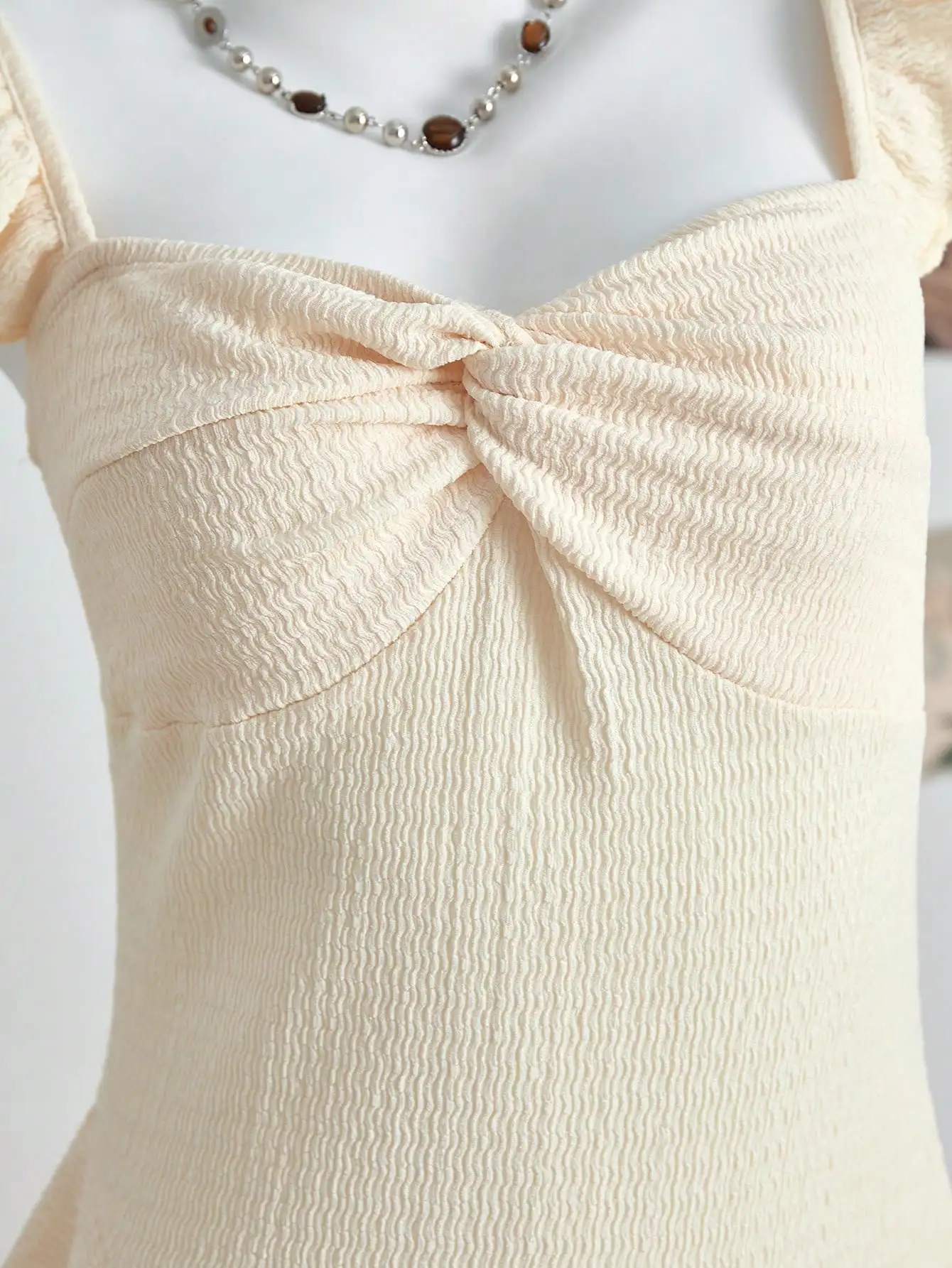 

Кремовое мини-платье с рюшами по низу, бантом и рукавами с воланами