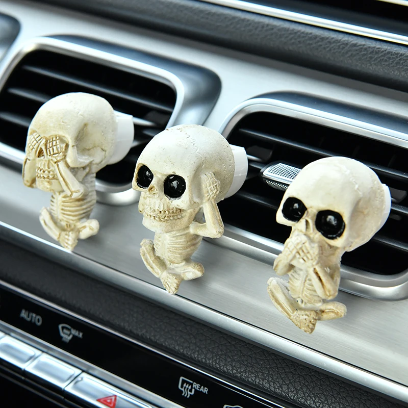 Kreative Auto-Totenkopf-Ornamente mit dem Motiv 'Sehe nichts Böses, höre nichts Böses, sprich nichts Böses', die als Auto-Innendekoration dienen.