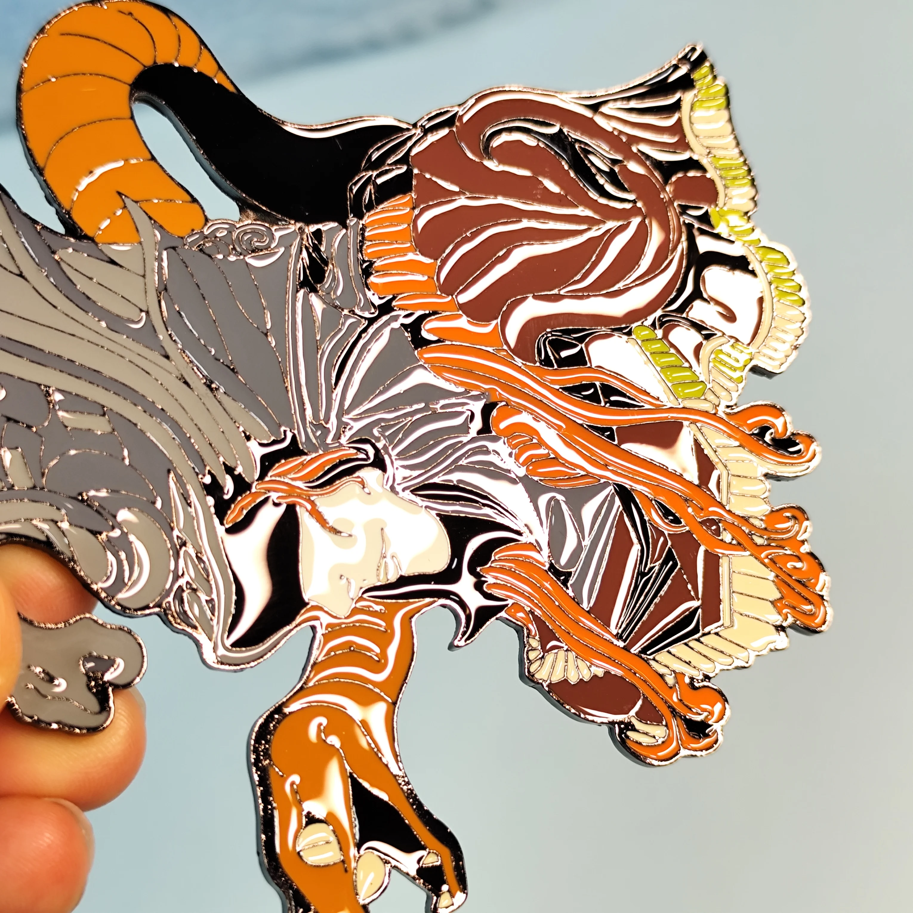 Enamel pin featuring a dynamic design with serpents and a figure. Intricate details, glossy finish—perfect for collectors.