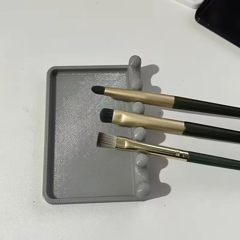 A portable holder for paintbrushes with a drip tray to prevent staining the table surface