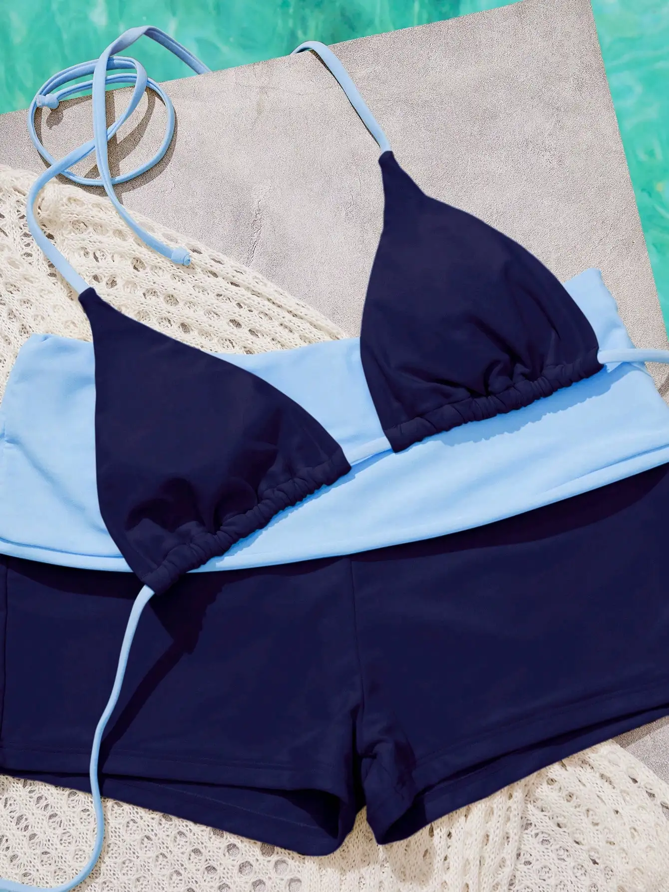 

Темно-синий треугольный топ-бикини с голубой отделкой и подходящими шортами с высокой талией для летнего пляжного отдыха.