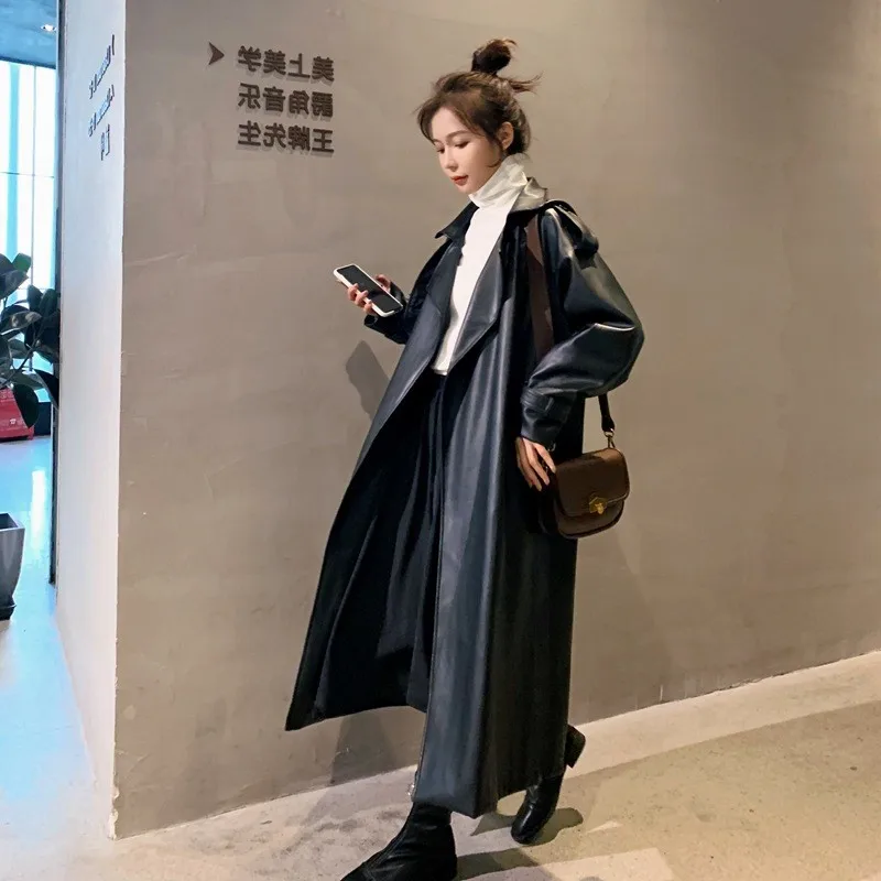 

A loose knee-length black motorcycle leather trench coat for women with lapel cinched waist and tie