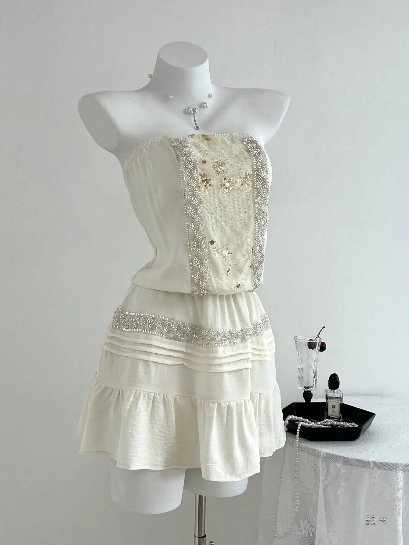 

Элегантное мини-платье с открытыми плечами, украшенное пайетками, бисерными аппликациями и многоярусной юбкой с рюшами.