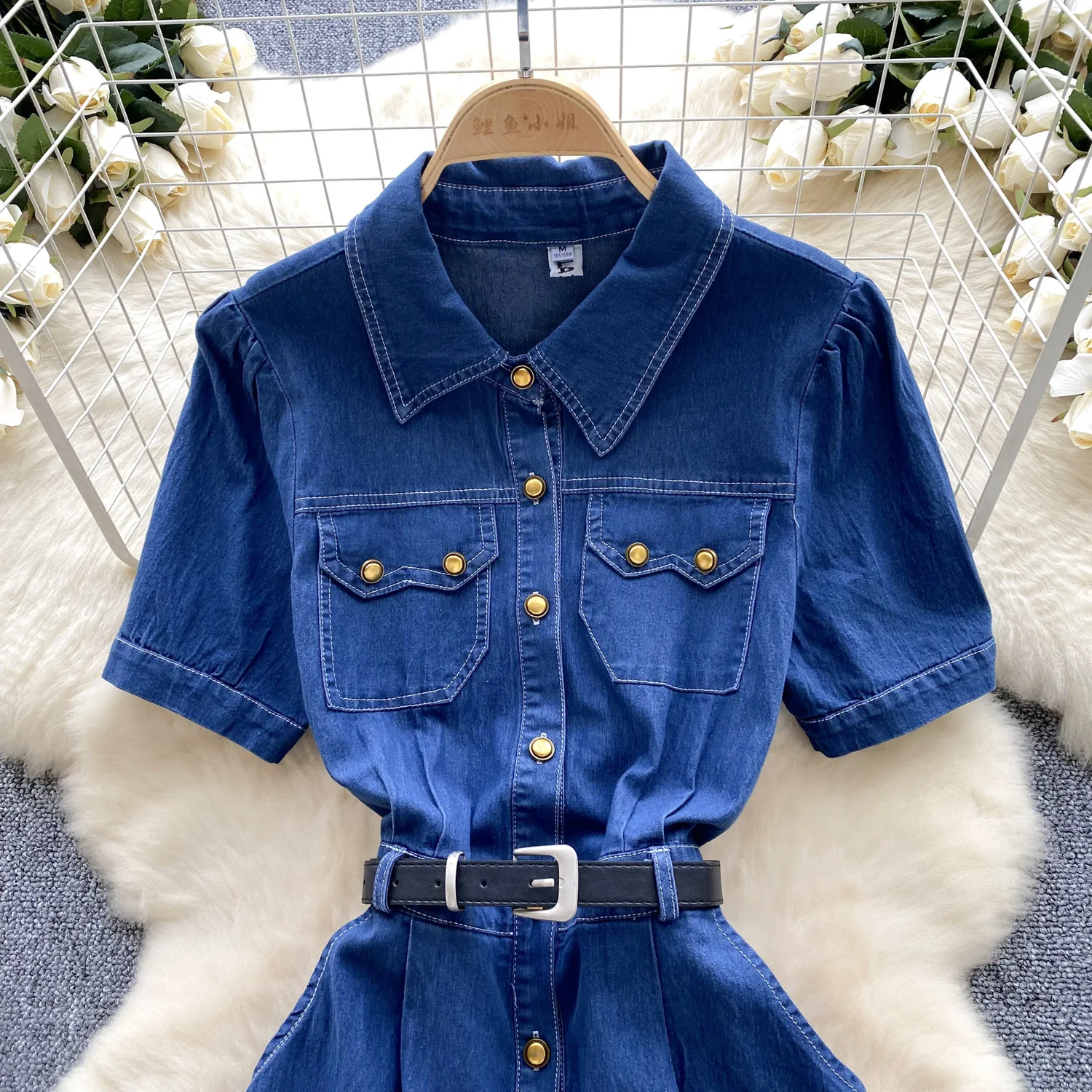 Un nuovo abito in denim alla moda estiva. Abito in denim a vita stretta con cintura monopetto in metallo a maniche corte con collo alto retrò per le donne