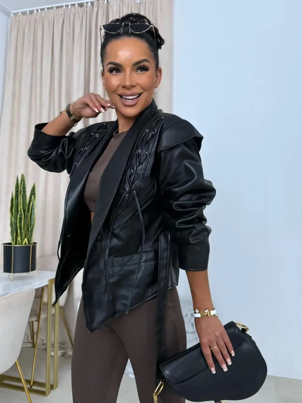 Krótka skórzana kurtka damska sznurowana, dopasowany krój, dekolt w serek, podkreślająca talię, jesienna moda damska, casualowa odzież wierzchnia w stylu streetwear.