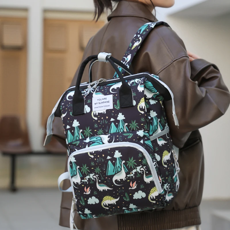 A lady hand-held mini mummy bag, cute dinosaur print backpack, suitable for daily use with a baby