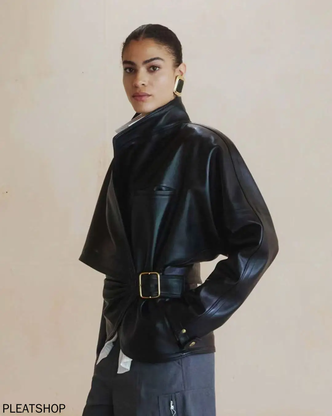 Awangardowa i swobodna kurtka damska na jesień/zimę z ekologicznej skóry proteinowej, modelująca talię, zapinana na klamrę, w stylu owijanym, z stójką.