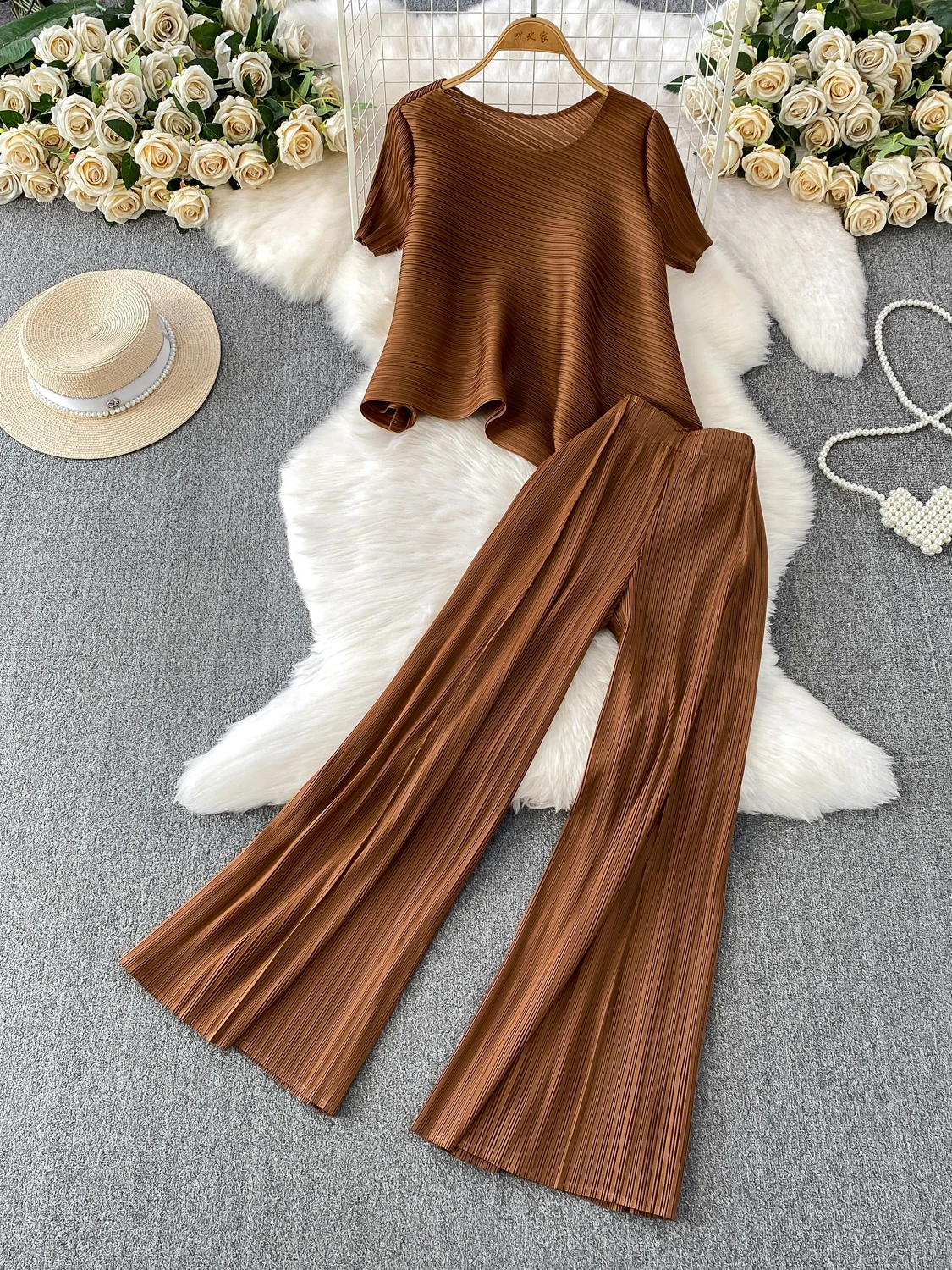 

Модный комплект из двух предметов: эластичная плиссированная асимметричная футболка с круглым вырезом и прямые широкие брюки с высокой талией.