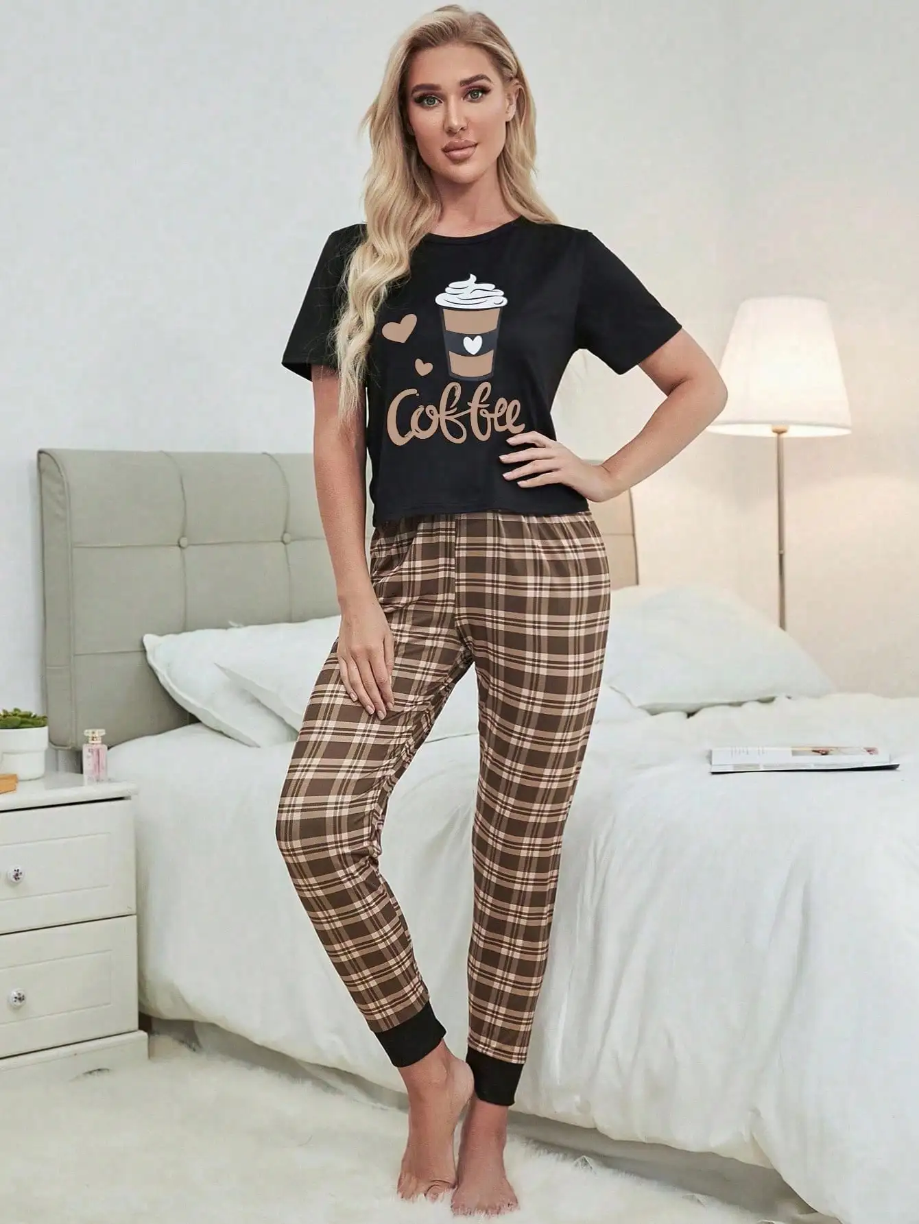 

Черный топ с короткими рукавами и графическим принтом в комплекте с коричневыми клетчатыми брюками для отдыха.