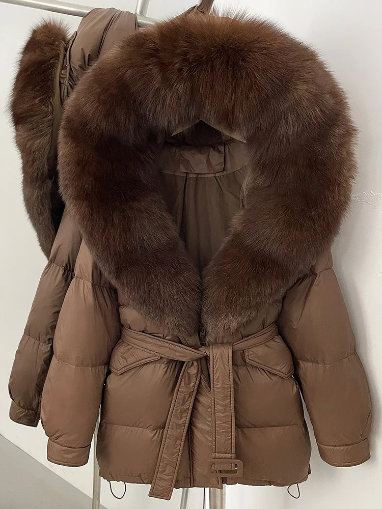 جديد 2025 سترات نسائية فضفاضة دافئة بقلنسوة مع حزام سميك دافئ متوسط الطول معطف منتفخ بياقة من فرو الثعلب الحقيقي معطف أبيض مبطن للأسفل