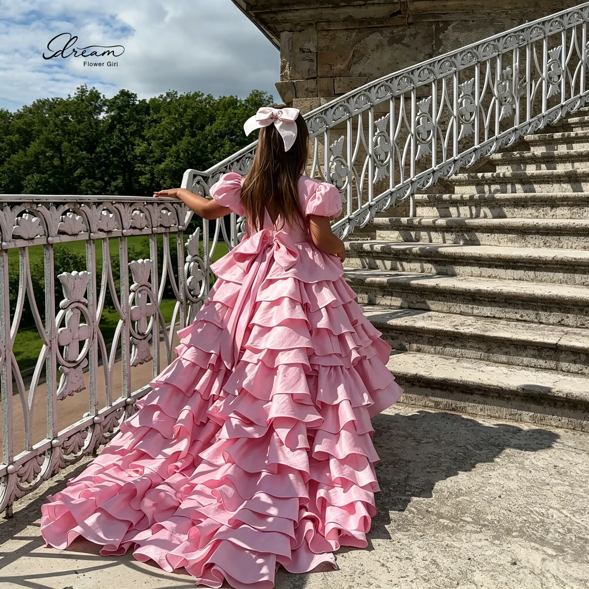 Formal Children's Gown Pink Floor Length Ball Gown featuring Puff Sleeves a Wide Lace Trimmed Skirt and a Bow Tie at the Back