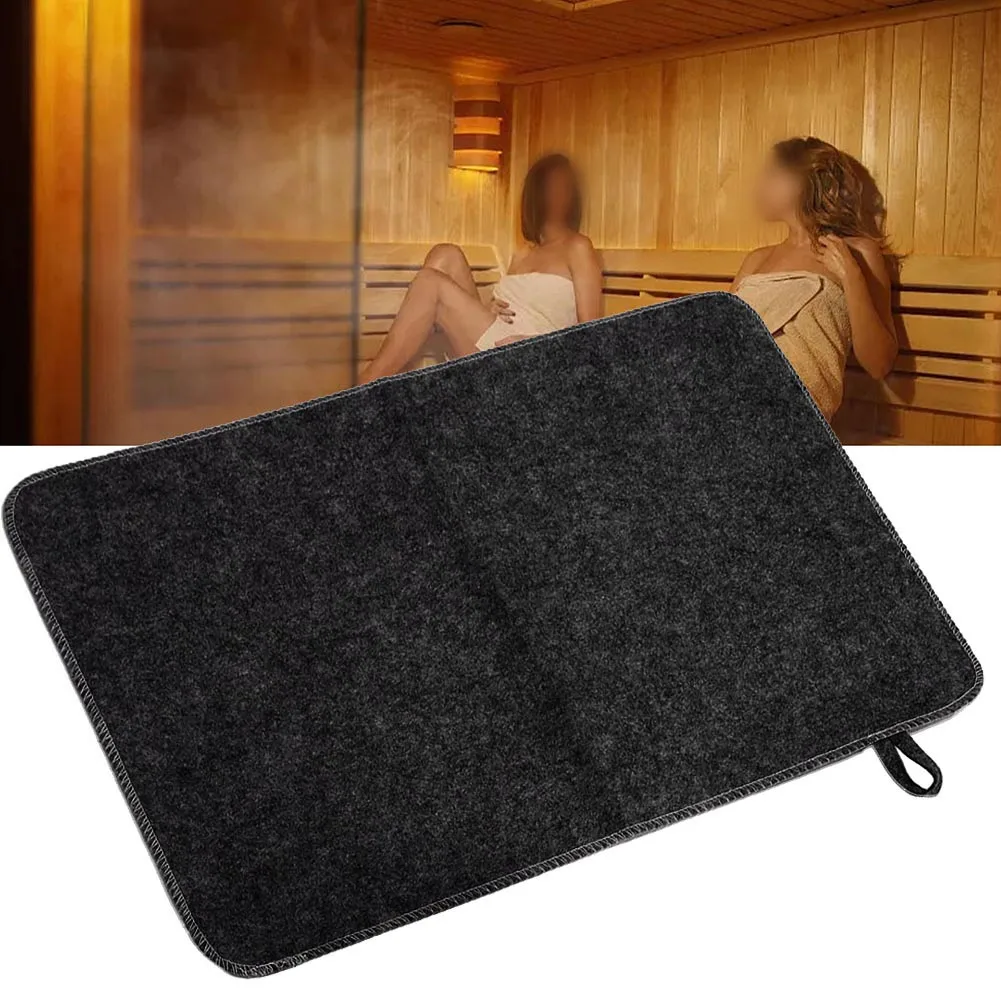 Gray felt sauna mat on a wooden bench in a steamy spa shower room.