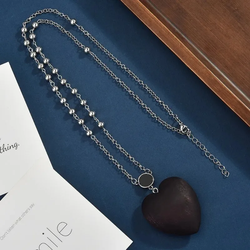 Uma corrente de suéter de contas elegante e versátil, um longo colar de madeira em forma de coração de outono e inverno para mulheres
