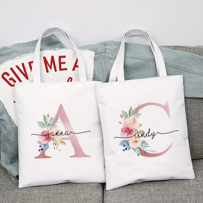 

Женская персонализированная белая холщовая сумка на плечо с розовым буквенным цветком, универсальная сумка на плечо для повседневного использования