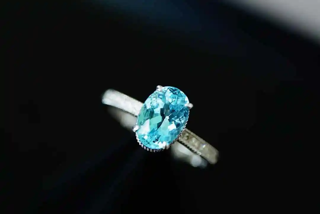 

1.75 carat oval-cut aquamarine, displaying brilliant fire, set in an 18-carat gold mount and adorned with diamond accents.