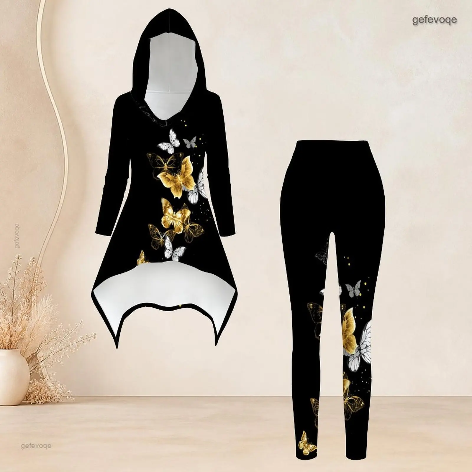 Conjunto de dos piezas para mujer: top de manga larga con capucha y estampado de mariposas doradas y blancas, corte asimétrico y pantalones ajustados.