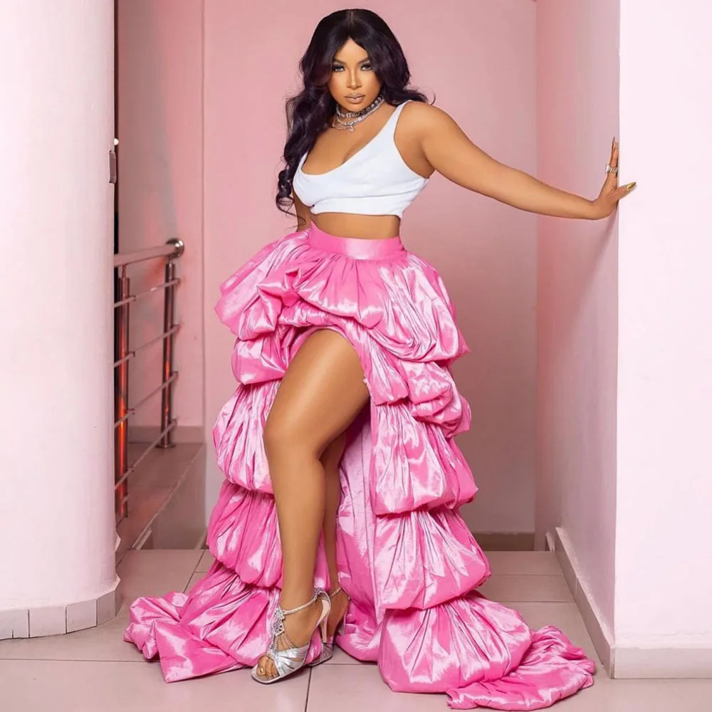 

Розовая многослойная юбка с высоким разрезом и струящейся тканью, украшенная яркими оборками и длинным шлейфом, в сочетании с серебристыми босоножками и белыми туфлями.