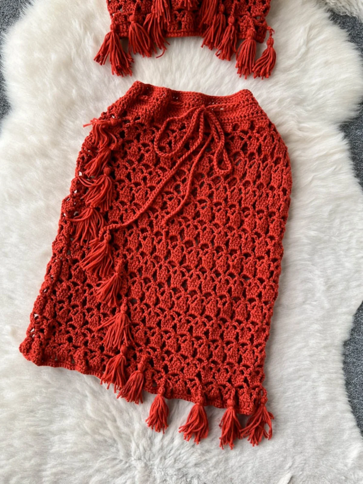 Conjunto de duas peças com top bustiê boêmio vazado com franjas e decote em V e saia curta justa, moda primavera verão fena.