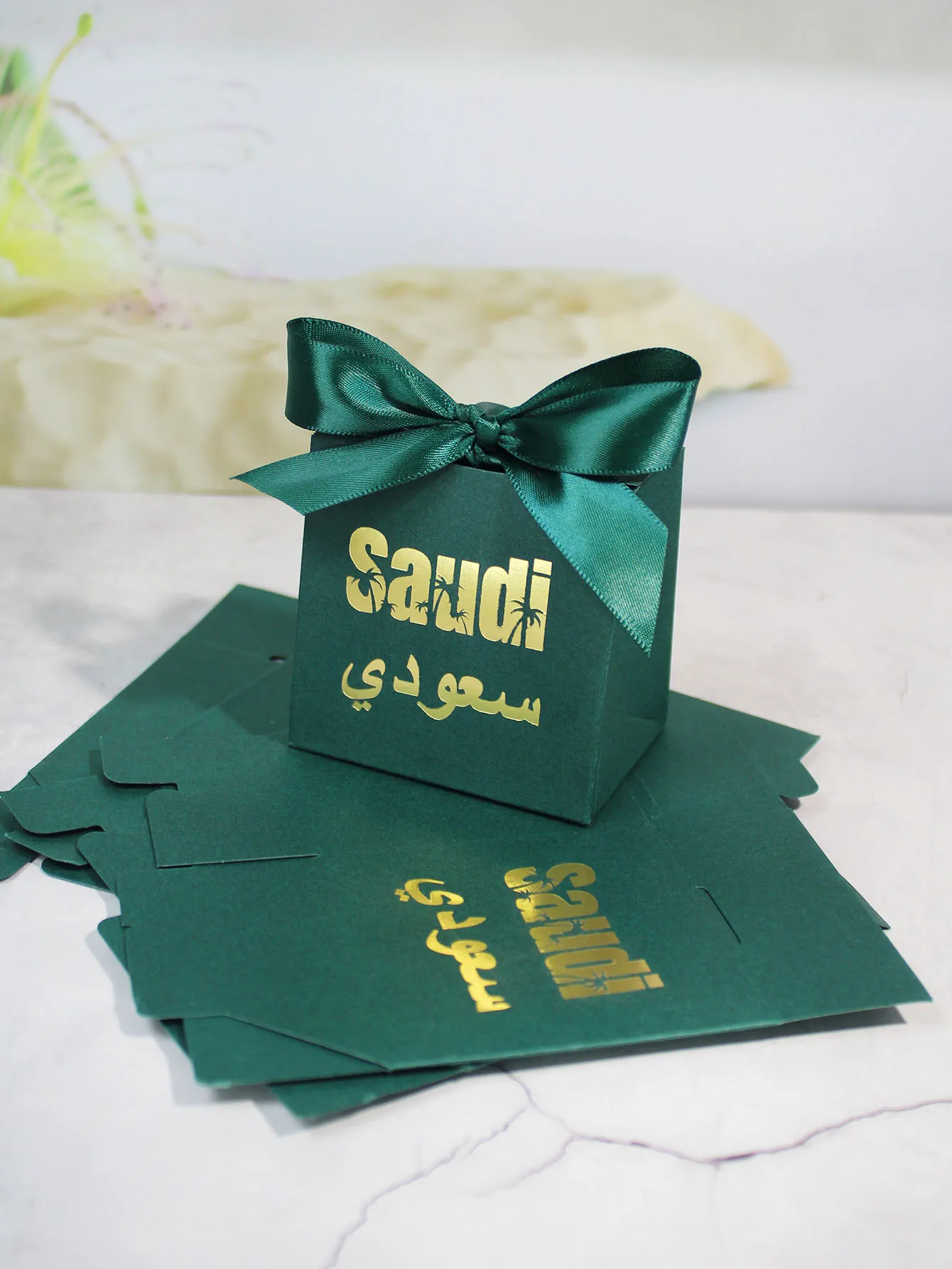 Charming green gift boxesDecorated with gold lettering, hollowed out palm trees, and Arabic script, ideal for festive events