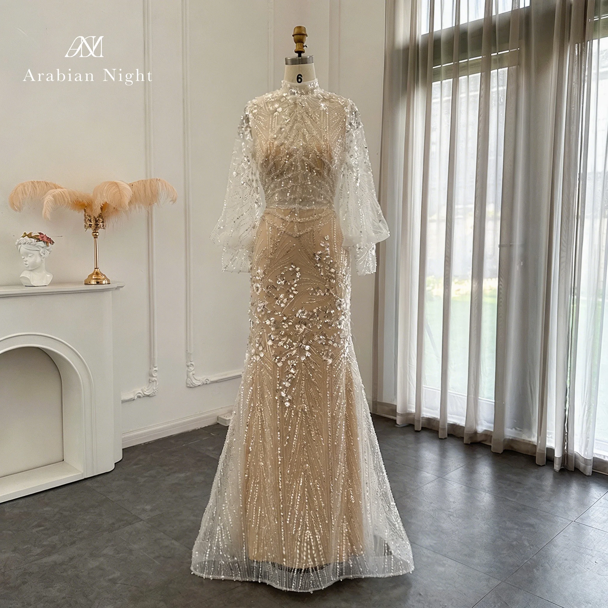 Champagne-colored floor-length long-sleeved formal mermaid gown featuring a high neck and metallic beaded embellishments