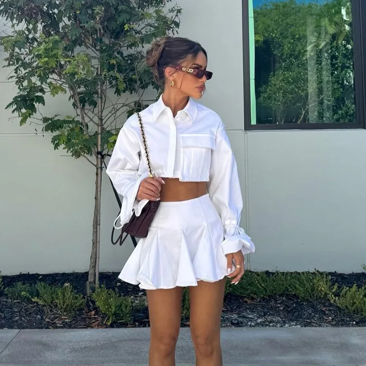 

Новый модный женский комплект из двух предметов: белый короткий топ с расклешенными рукавами с лацканами и плиссированной юбкой.