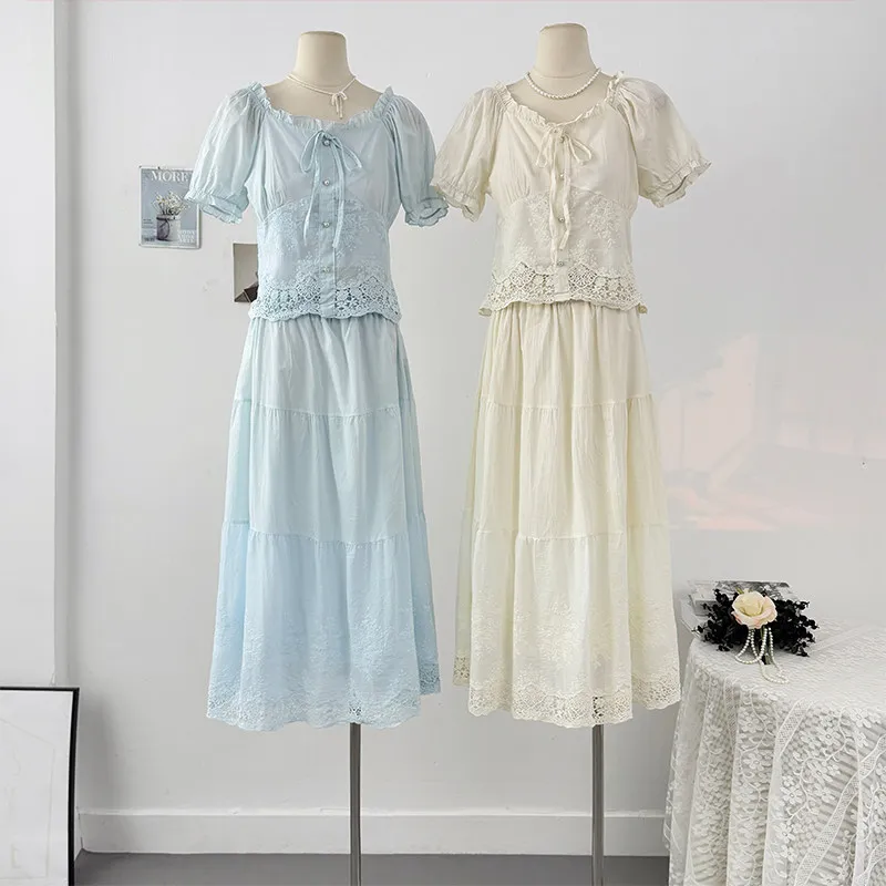 

Комплект женский летний: блузка с вышивкой в виде цветов, рукавами-фонариками и шнуровкой + юбка-макси с высокой талией и многослойным дизайном