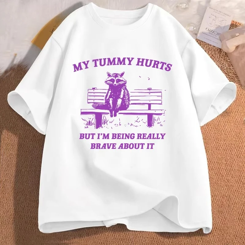 Camiseta Feminina e Masculina com Estampa Gráfica Engraçada de Meme Racco: 'Meu Estômago Dói, Mas Estou Sendo Muito Corajosa Com Isso'