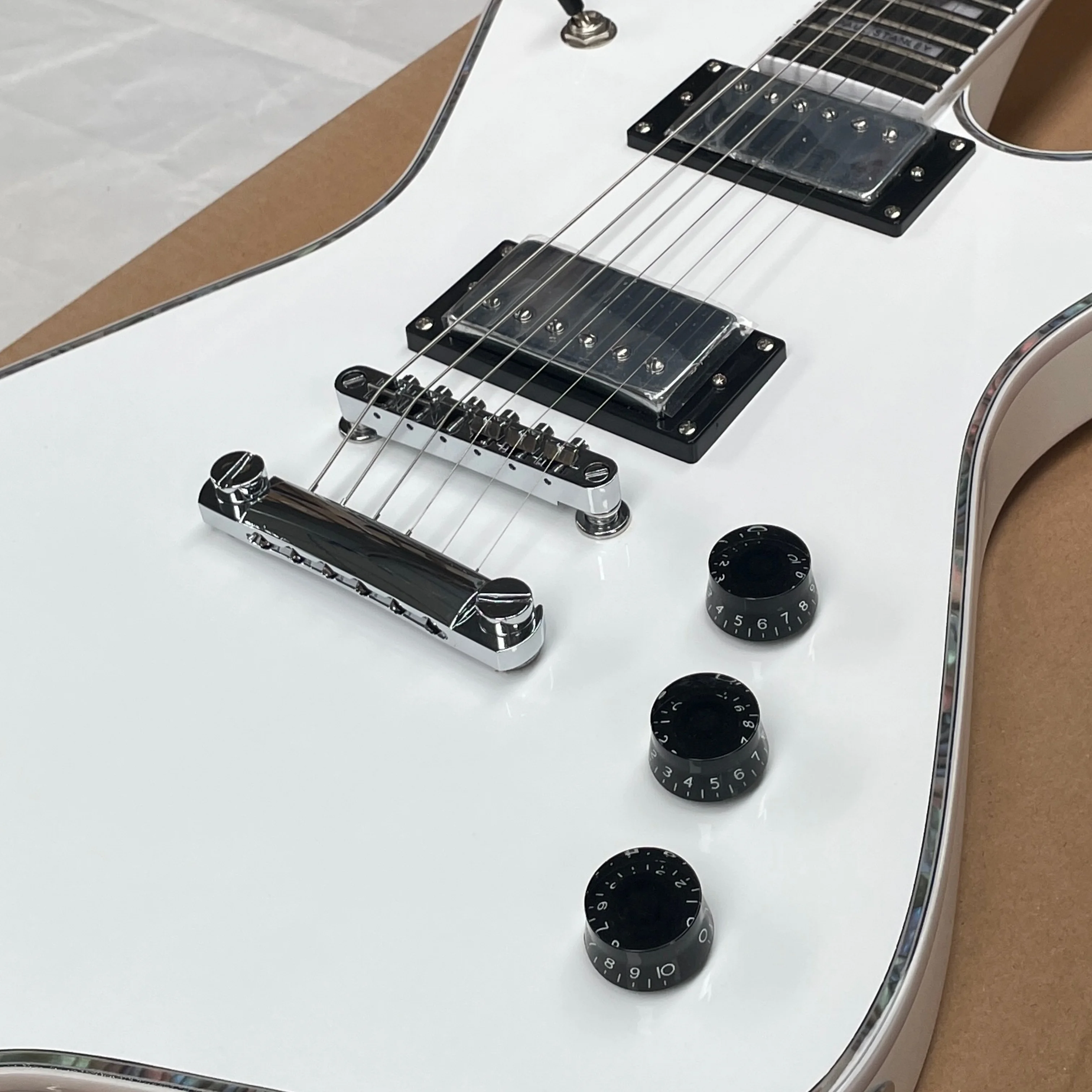 Guitare électrique blanche pure à 6 cordes avec touche en palissandre lisse, pont fixe, idéale pour les performances sur scène rock.