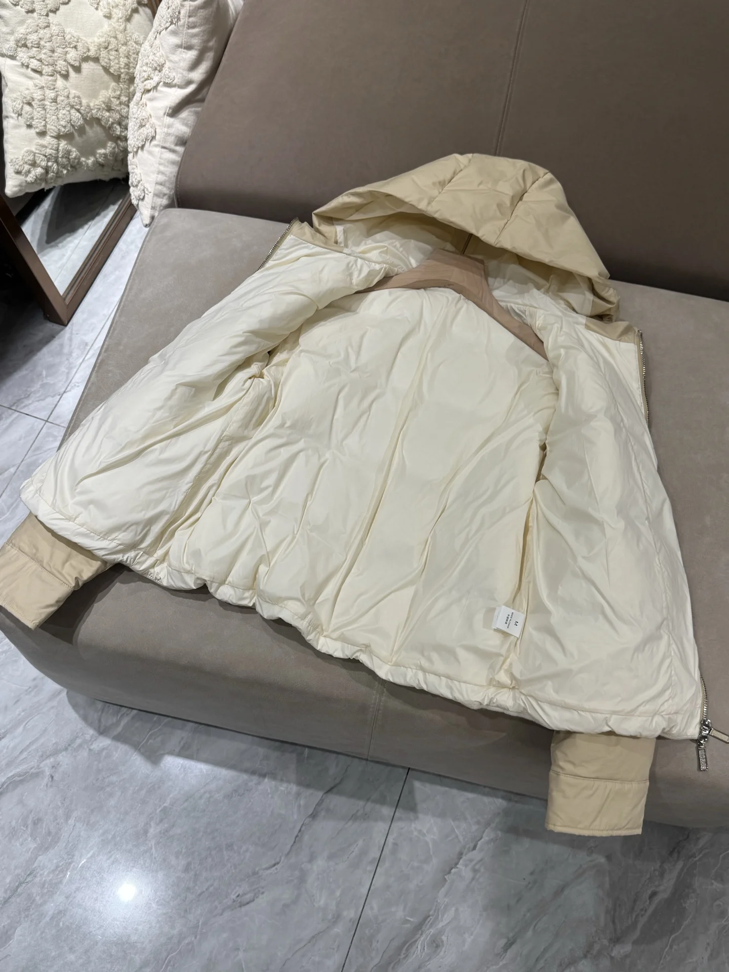 เสื้อแจ็คเก็ตขนเป็ดผสมแคชเมียร์ ขนสัตว์ และผ้าไหม พร้อมฮู้ด แต่งโซ่ประดับลูกปัด และแขนเสื้อแบบดรอปชอลเดอร์ เพื่อทรงสวยสง่า