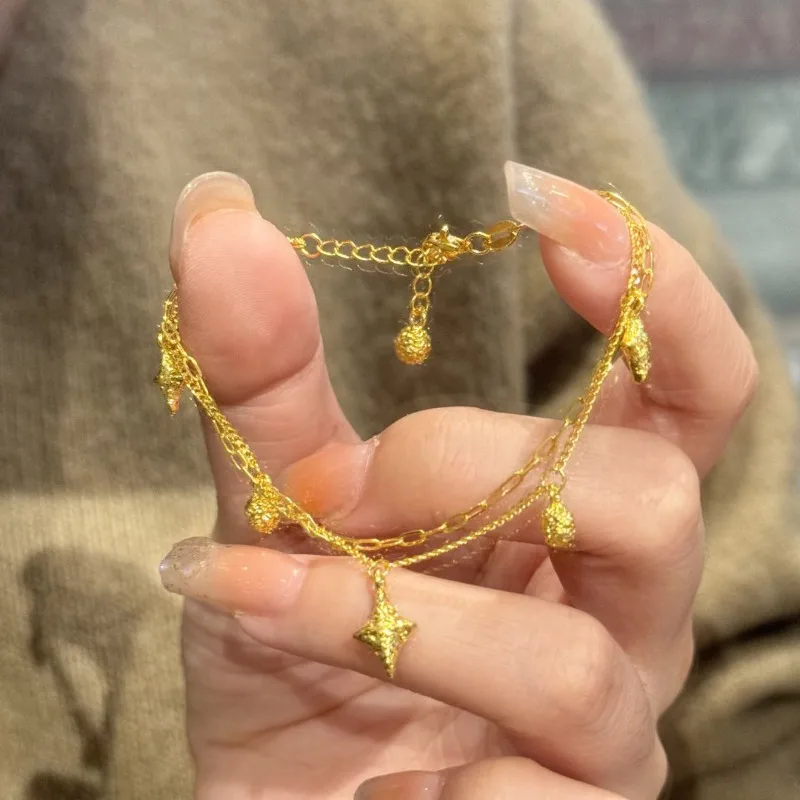 Bransoletka damska w stylu light luxury, złota, z gwiazdą czterokątną, niszowy design, wyrafinowany, podwójny łańcuszek, do noszenia warstwowo, ekskluzywna.