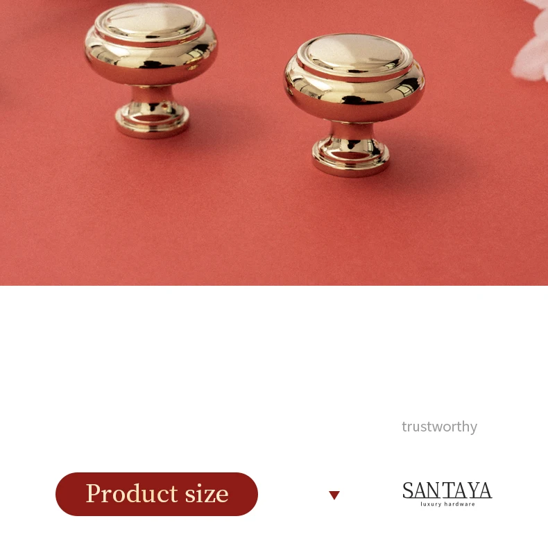 Pair of round gold cabinet knobs on a coral surface