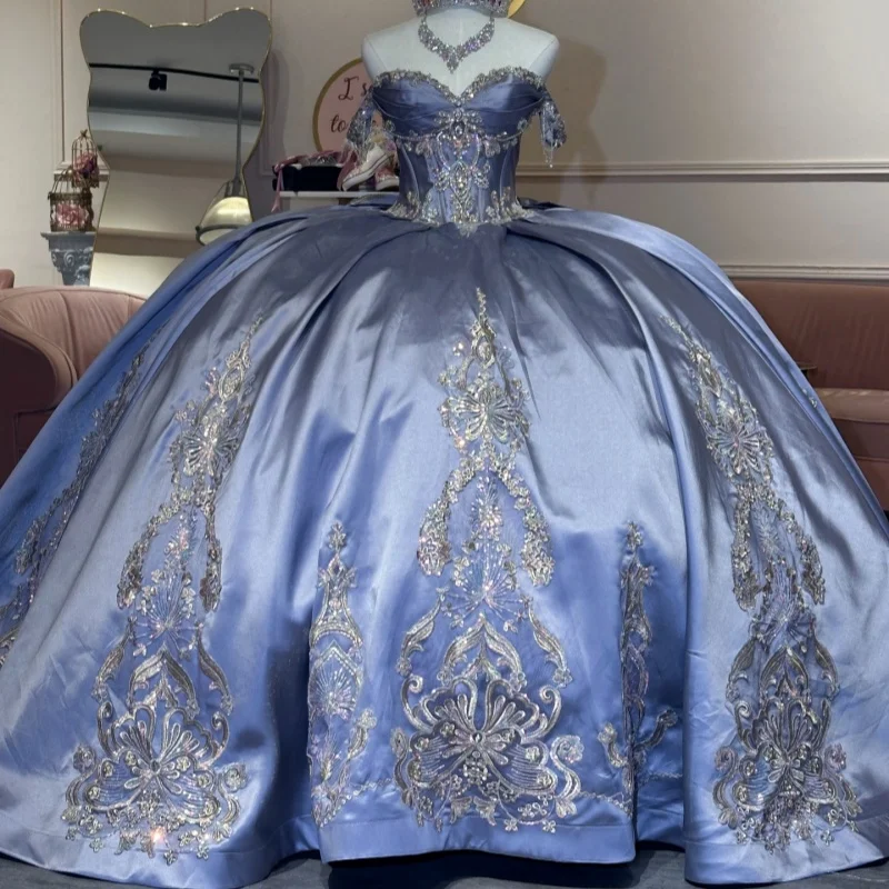 

Атласное платье для квинсеаньеры цвета сатинового тумана с открытыми плечами, блестящими кристаллами, бантом и длинным шлейфом. Индивидуальный пошив.