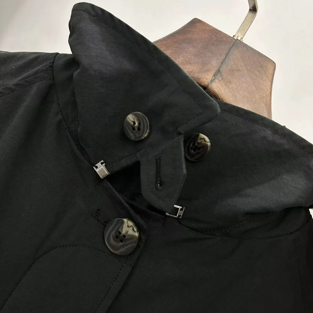 Jesienny płaszcz wiatrówka o klasycznym kroju, z wysokim rozcięciem, wykonany z mieszanki bawełny, o kroju litery A, średniej długości, zapinany na wiele guzików.