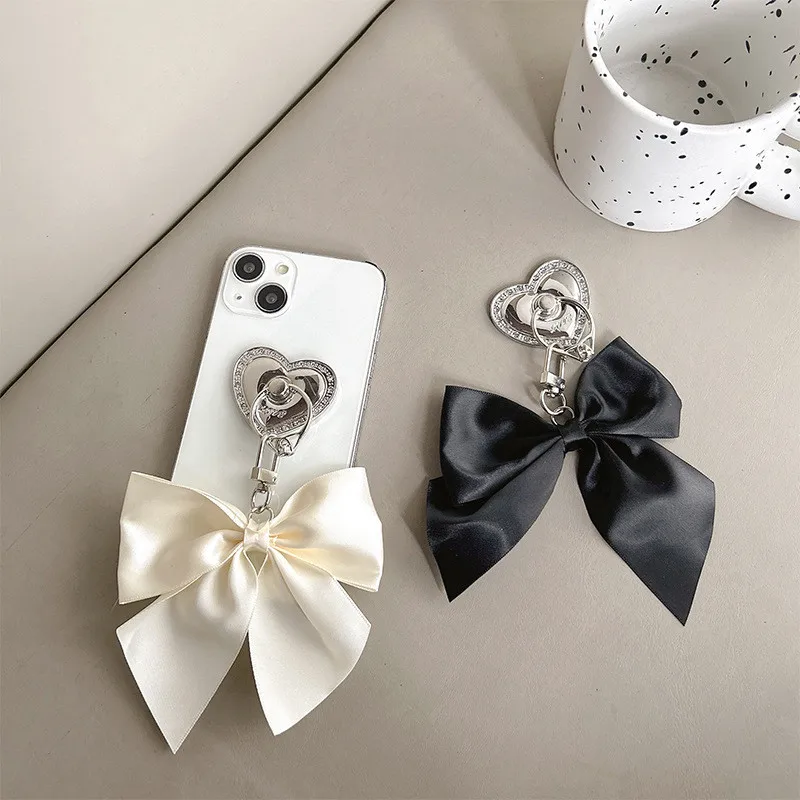 

Держатель для телефона с кольцом на палец, металлический, в форме сердца, с бантом из атласа, раскладная подставка-держатель для iPhone 16/17, кронштейн для мобильного телефона