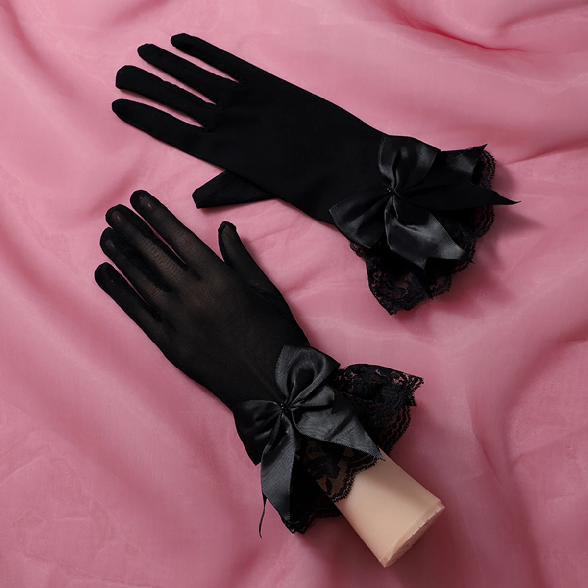 Un par de guantes negros con decoraciones de lazo, adecuados como accesorios para bodas de novia o bailes de mujer