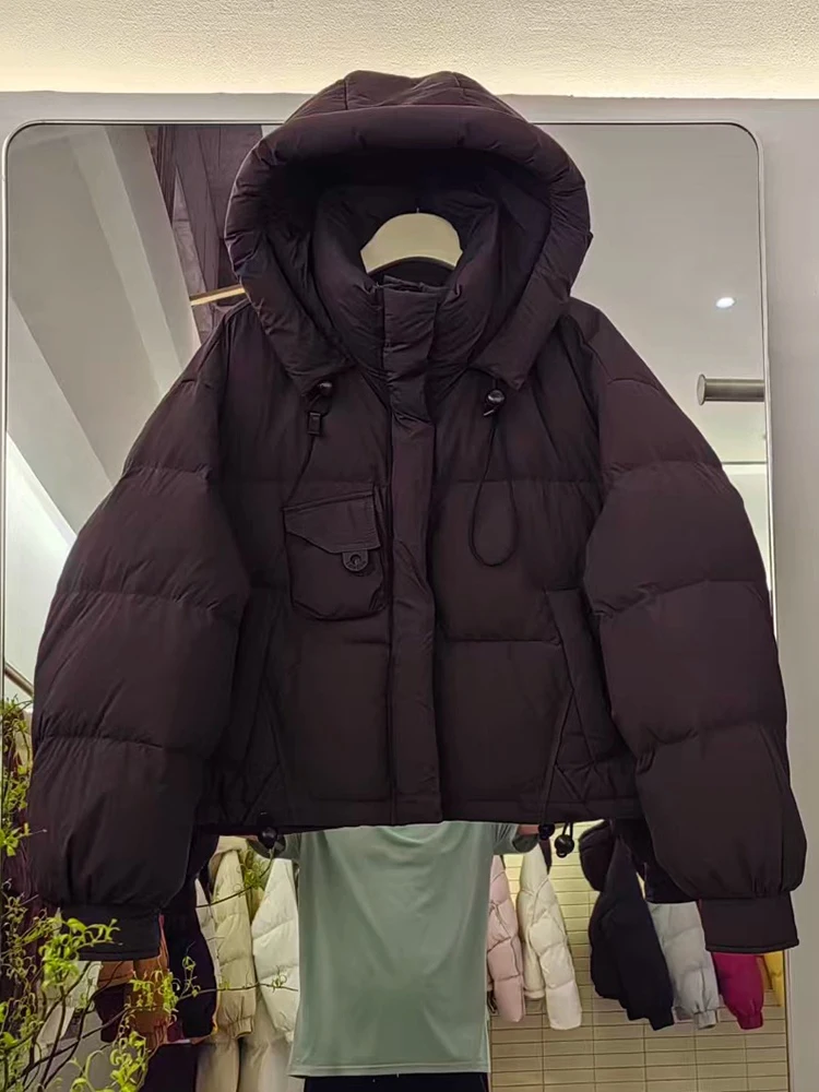 เสื้อแจ็คเก็ตขนเป็ดสำหรับผู้หญิง รุ่นใหม่ ปี 2025 ฤดูหนาว แบบสั้นมีฮู้ด สไตล์เกาหลี หนา ทรงขนมปัง อเนกประสงค์ ขนเป็ดขาว  เสื้อโค้ทแฟชั่น