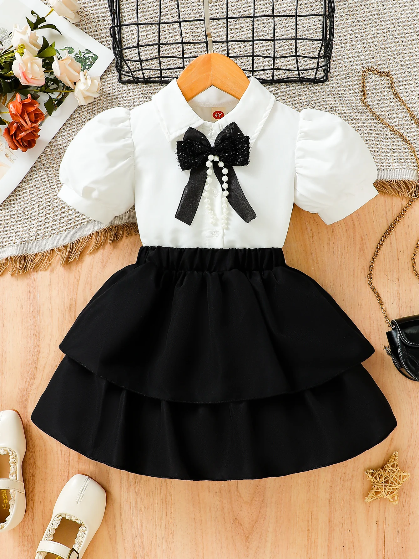 The new summer girls\' bubble-sleeved blouses are paired with bow accessories and a black half-length cake skirt