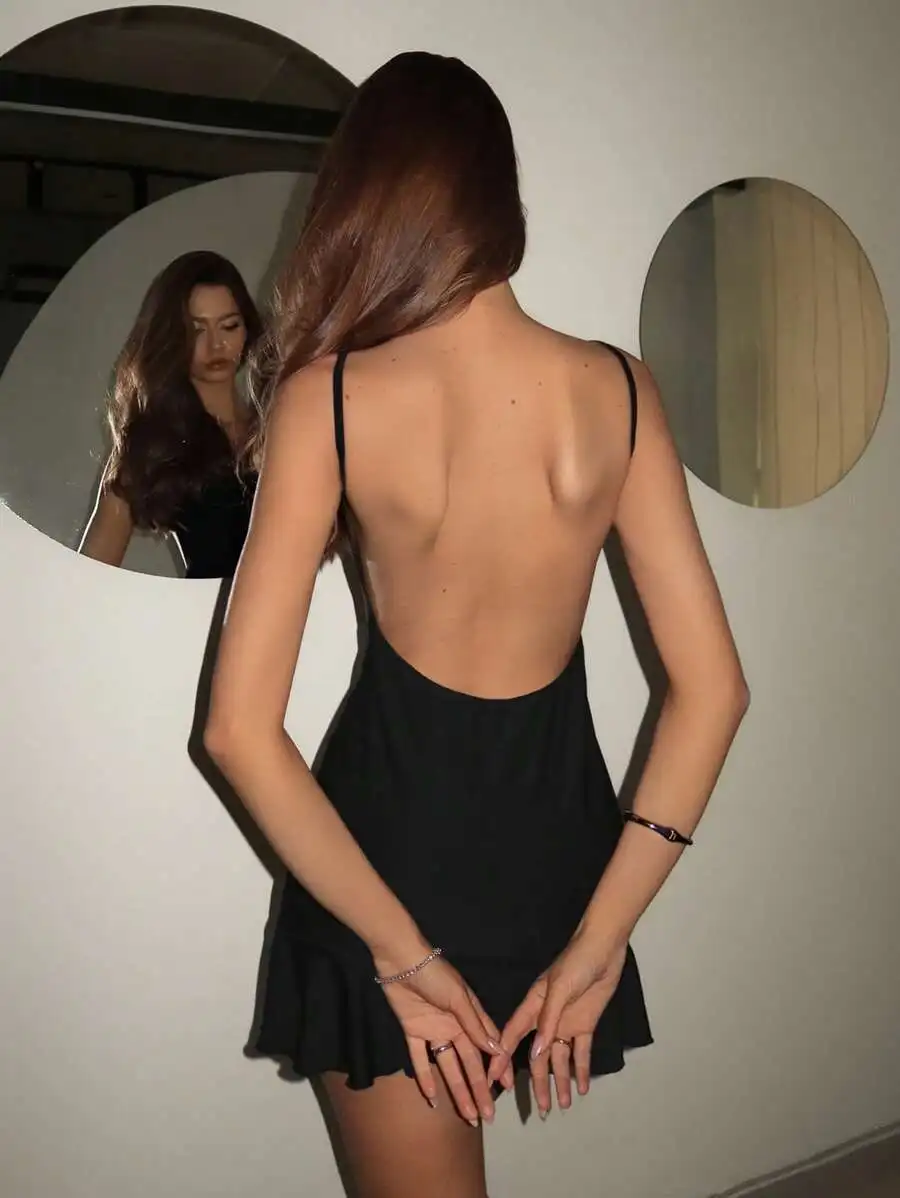 

Женское однотонное черное мини-платье на тонких бретелях с открытой спиной и рюшами по низу