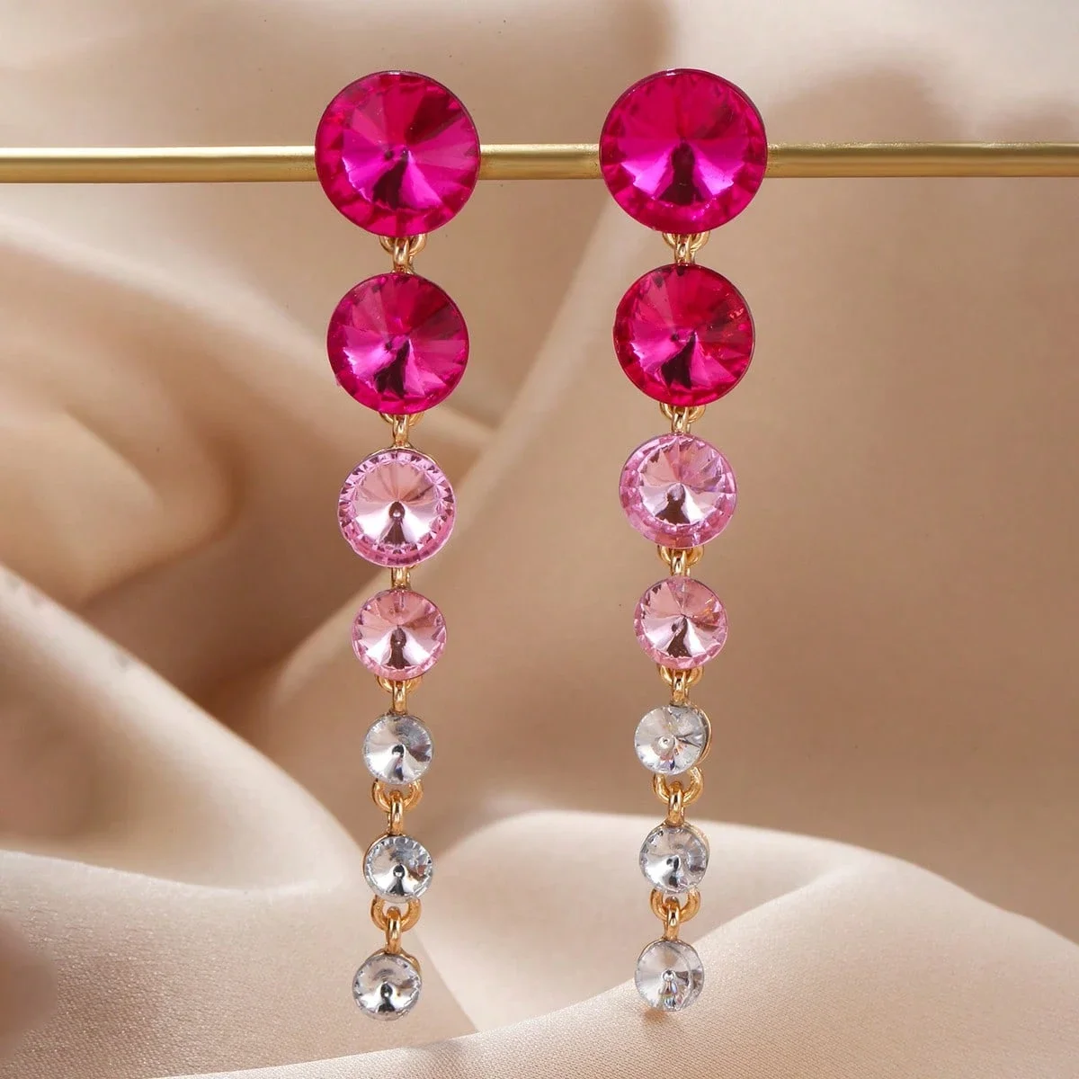 Pendientes de cristal en tono dorado con múltiples filas y piedras degradadas de fucsia a transparente