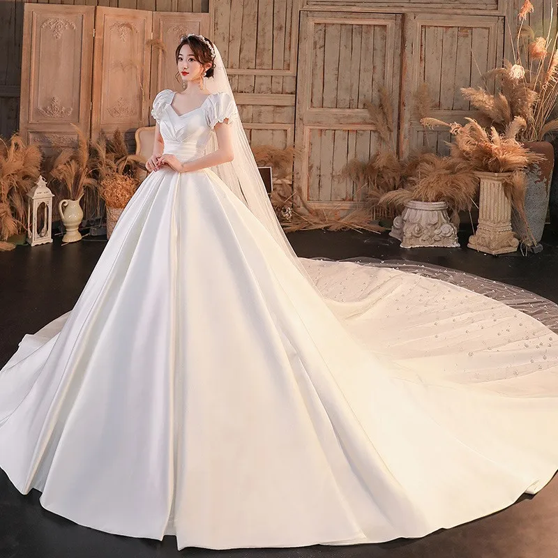 肩が一つになったサテン生地のドレスで、腕を覆う大きなトレーンが付いています。