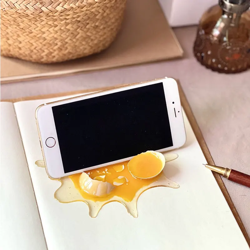 Realistischer Handyhalter mit gebrochenem Ei, lustiges Streichspielzeug mit Dekompressionsstütze für Schreibtischdekoration, Gag-Geschenk für Freunde