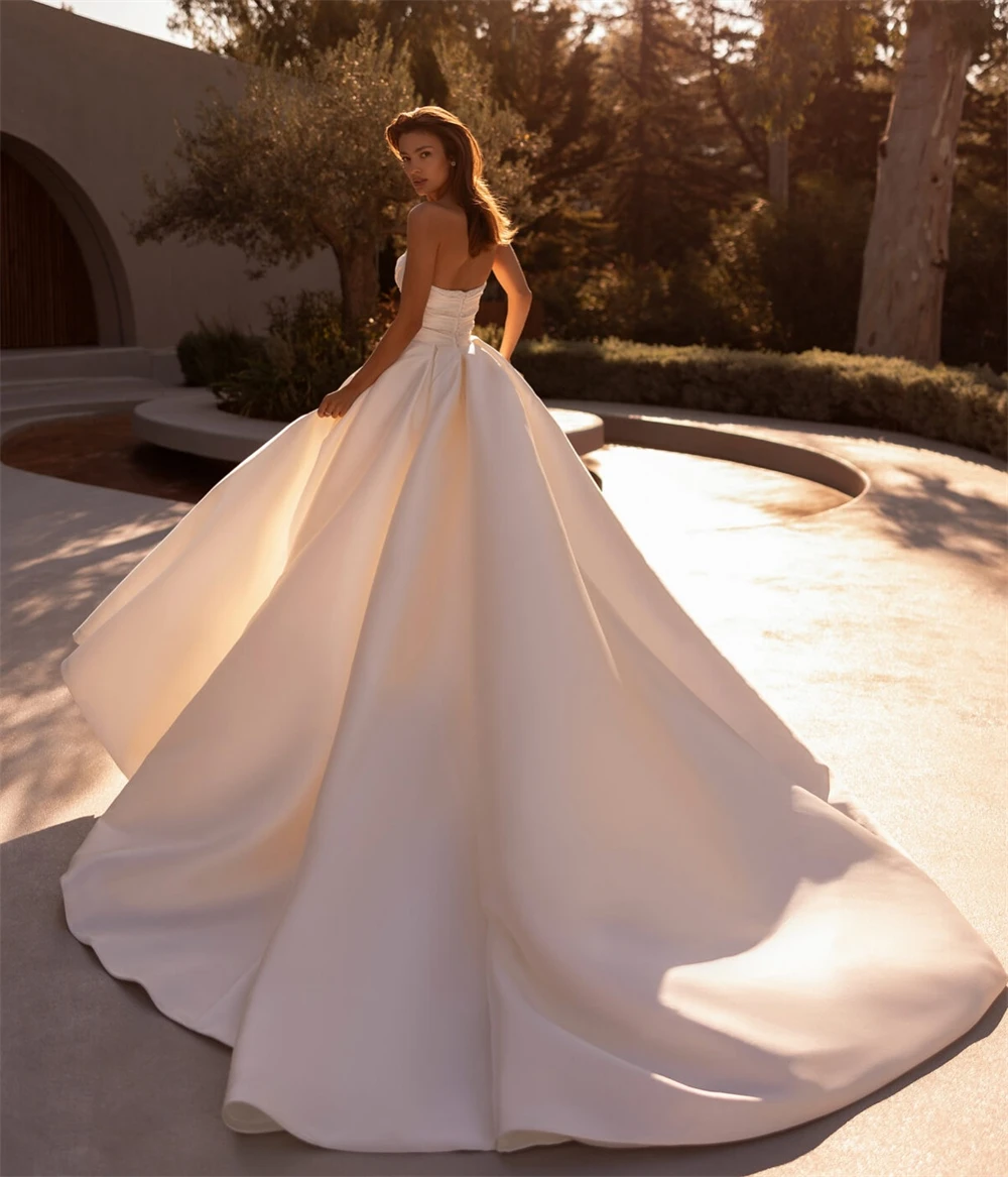 فستان زفاف أنيق من الساتان الأبيض مخصص رسمي على شكل قلب بدون أكمام زي العرائس بوهو على شكل حرف a ذيل شابيل فيستدو دي نوفيا