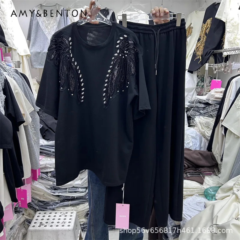 

Весенний комплект из двух предметов: футболка свободного кроя с короткими рукавами и узором в виде крыльев, украшенная стразами, и широкие брюки с эластичным поясом.