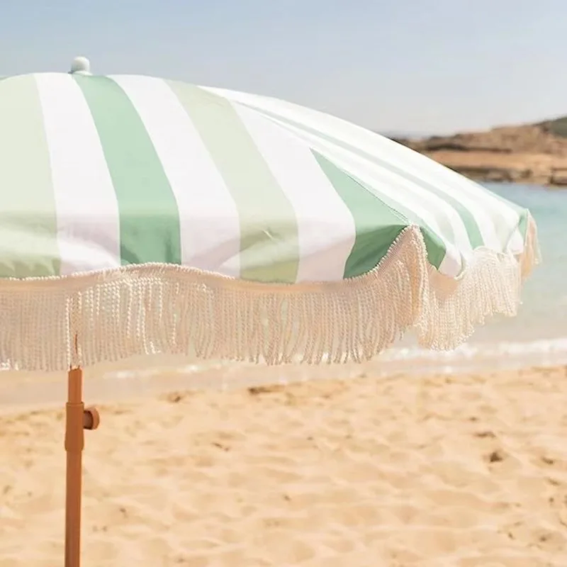 مظلة شرابة للشاطئ مخططة باللون الأخضر والأبيض والأصفر مع حماية من الشمس في الهواء الطلق