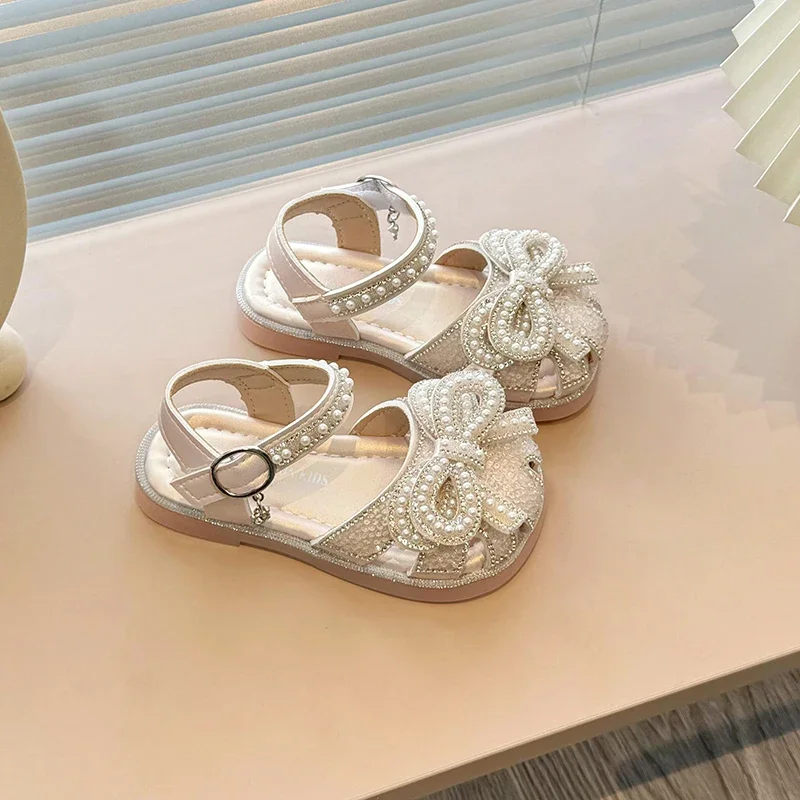 Sandalias planas elegantes para niñas, chanclas con lazo de perlas para niños, sandalias de princesa informales con diamantes de imitación, recortes de moda, sandalias de vestir para niños