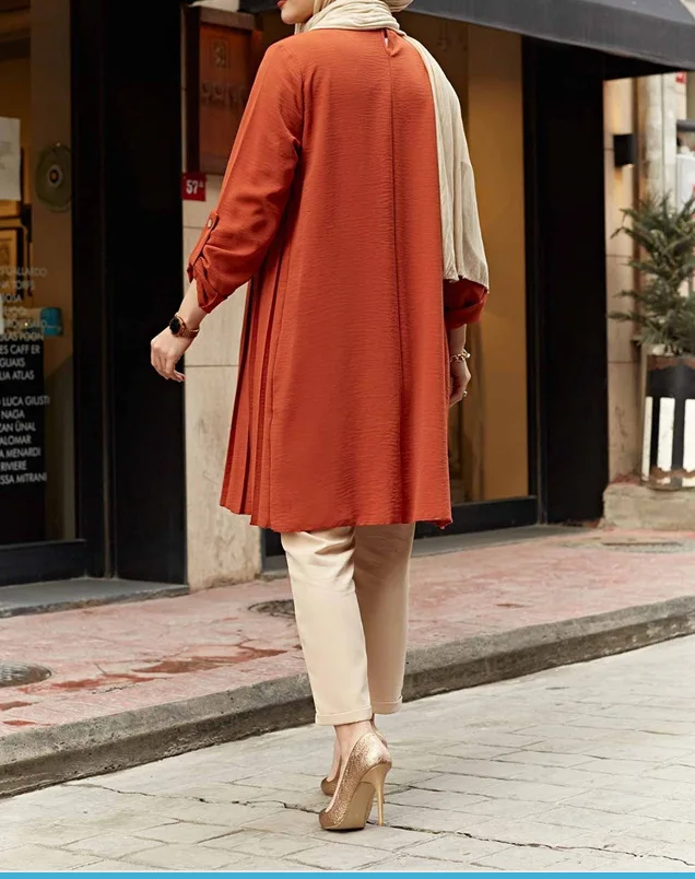 Back view of rust tunic showing the plain back and loose longline silhouette