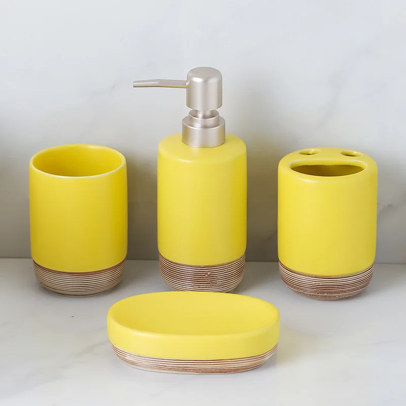 

Набор для ванной комнаты из четырех предметов: желтая бутылка для лосьона с деревянным узором, керамическая мыльница, аксессуары для подливки жидкостей.