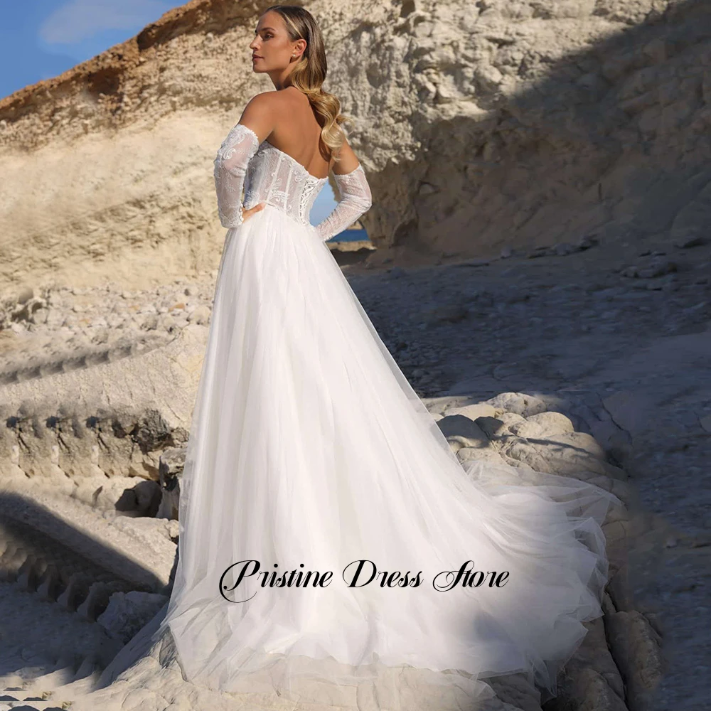 Suknia ślubna w stylu boho z odpinanymi rękawami, tiulowa, z rozcięciem z boku, sznurowana na plecach, dekolt w serce, zdobiona perłami, fason A-line, możliwość personalizacji.